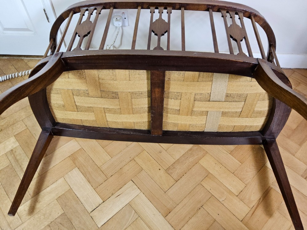 An Edwardian mahogany settee featuring a curved backrest with inlaid vertical splats, tapered legs, and a cream patterned upholstered seat. View VII