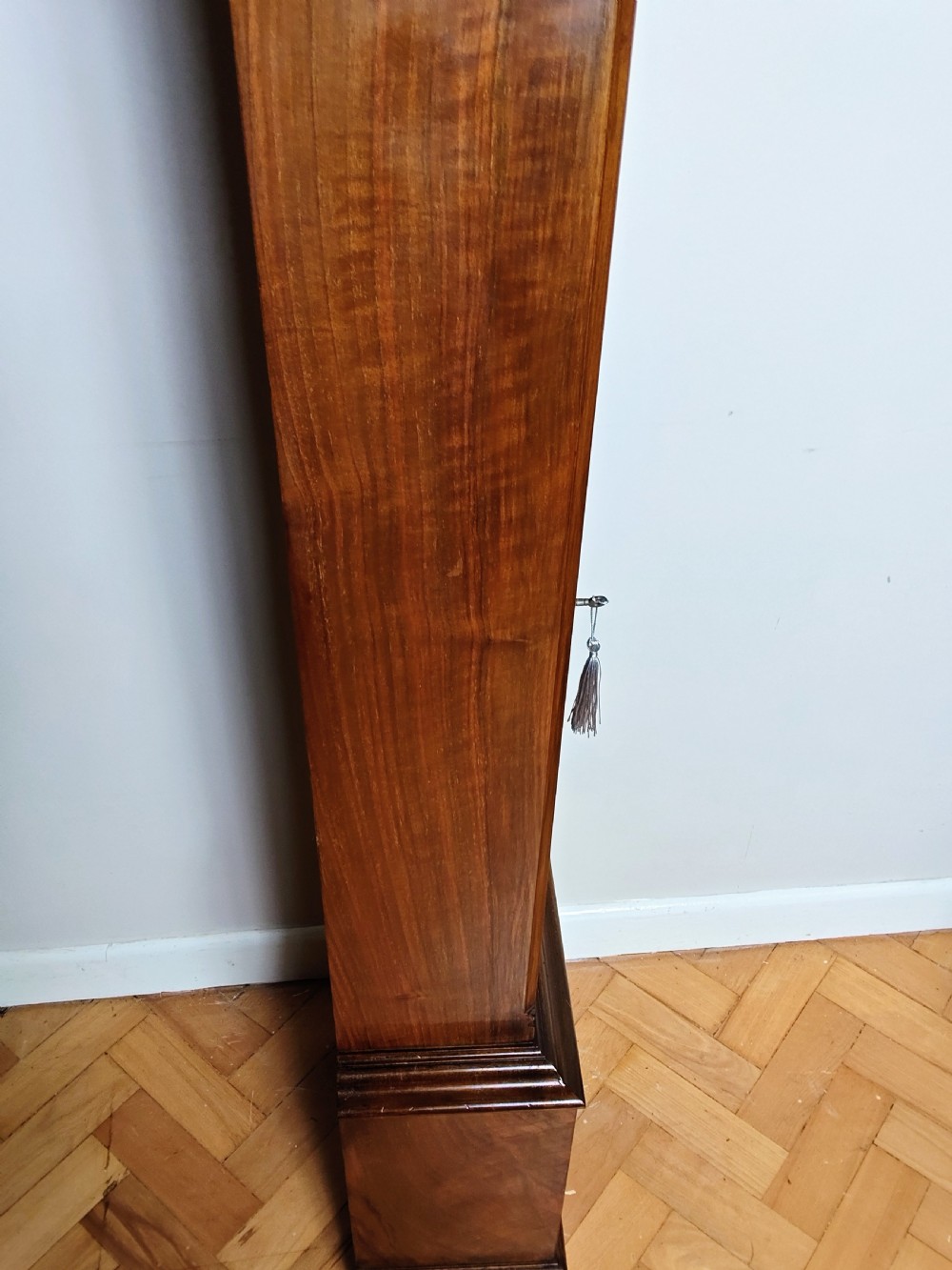 A tall burr walnut grandmother longcase clock featuring an arched hood, silvered dial with Roman numerals, and an arched trunk door. View XII