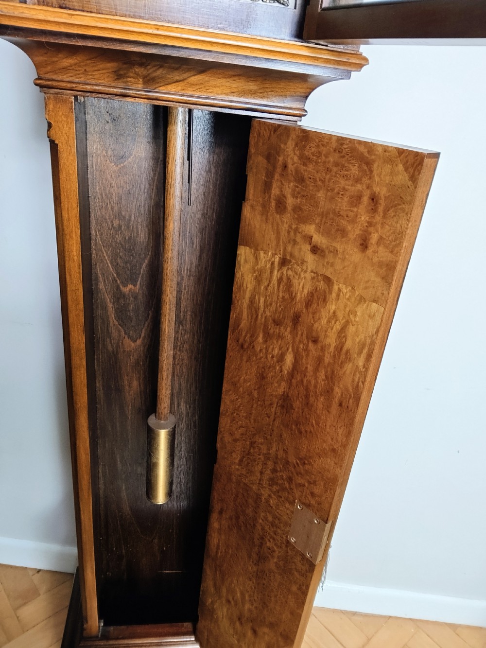 A tall burr walnut grandmother longcase clock featuring an arched hood, silvered dial with Roman numerals, and an arched trunk door. View XIII