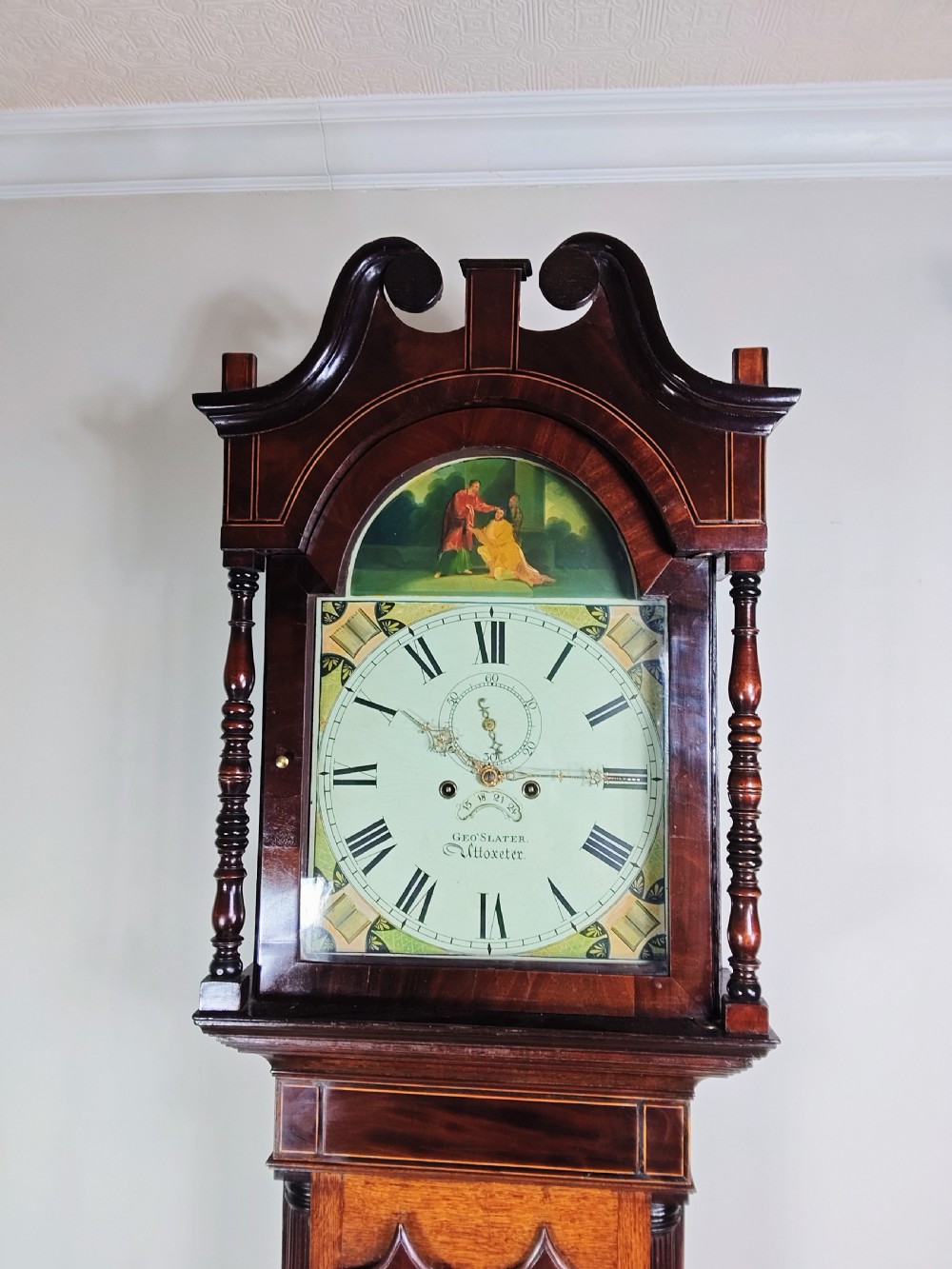 A Georgian oak and mahogany longcase clock featuring a swan-neck pediment, turned pillars, and a painted arch dial. View VII