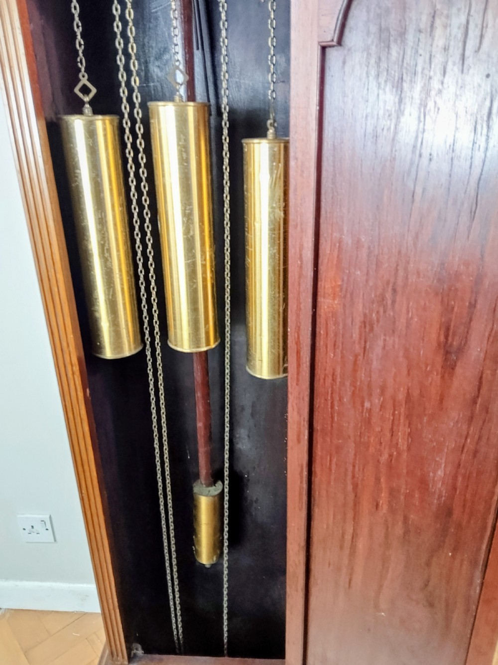 A tall mahogany longcase clock featuring an arched hood, glass door displaying a brass dial with silvered chapter ring, fluted side columns, and a moulded plinth base. View II