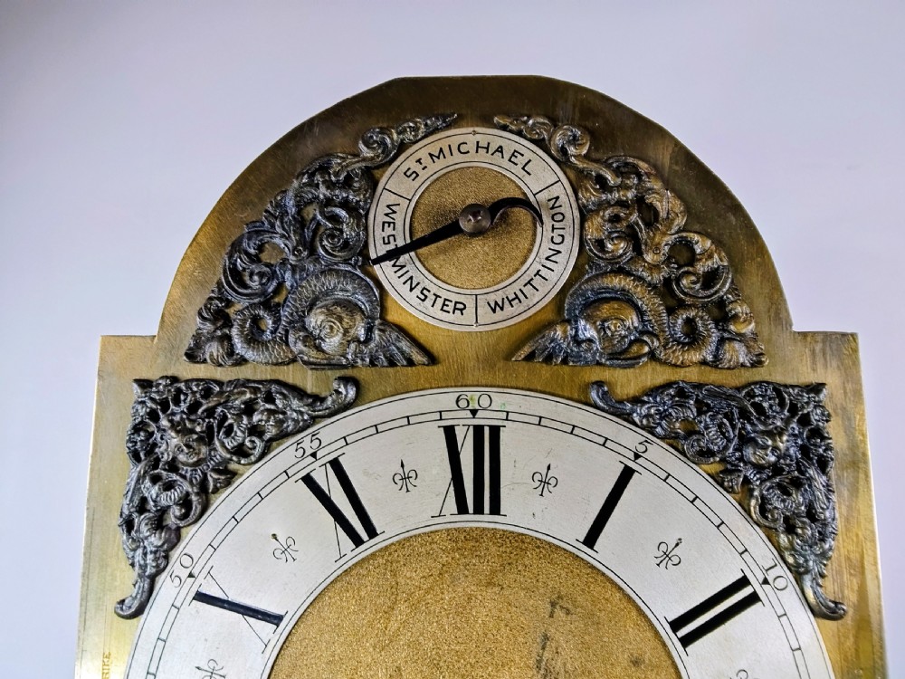 A tall mahogany longcase clock featuring an arched hood, glass door displaying a brass dial with silvered chapter ring, fluted side columns, and a moulded plinth base. View VIII