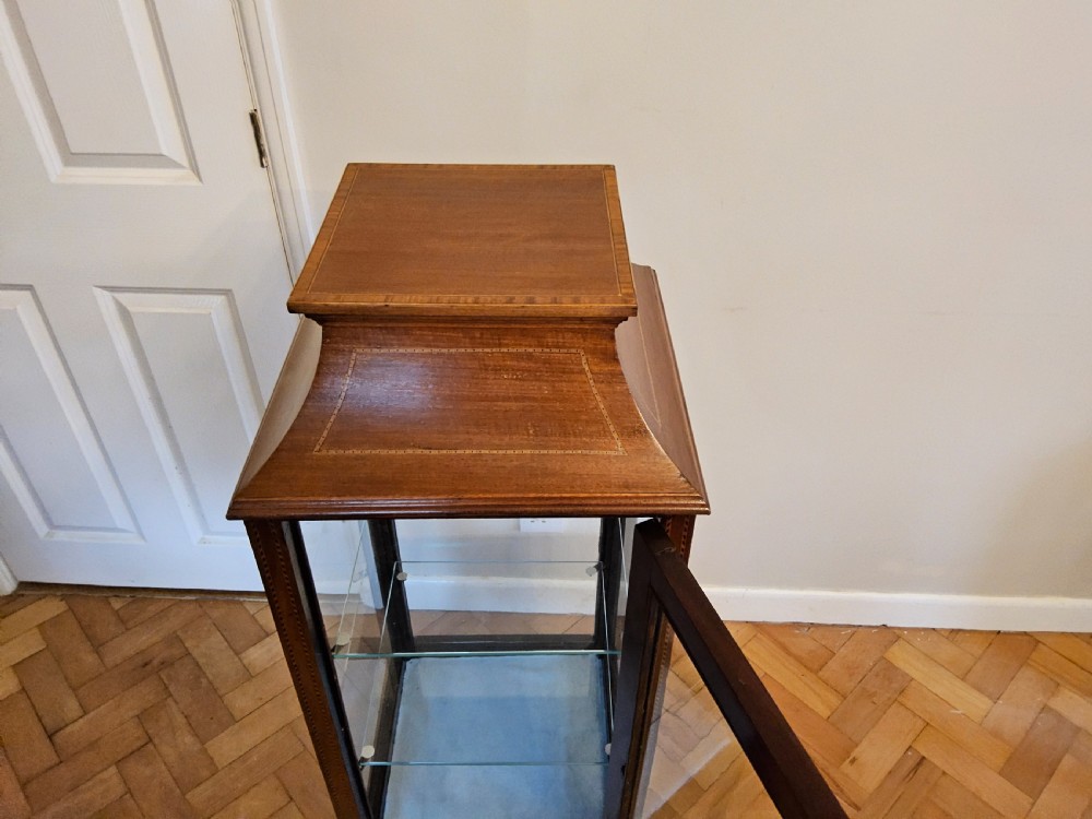 A slender mahogany bijouterie cabinet featuring four glass sides, two glass shelves, satinwood inlay details, and a stepped pagoda top. View VI