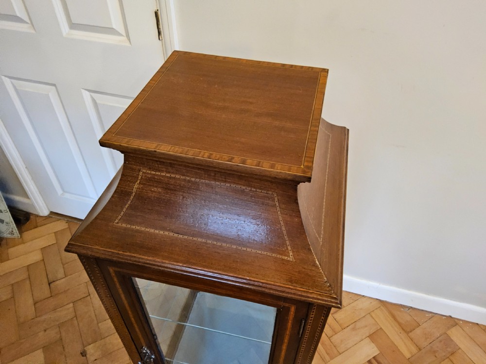A slender mahogany bijouterie cabinet featuring four glass sides, two glass shelves, satinwood inlay details, and a stepped pagoda top. View X