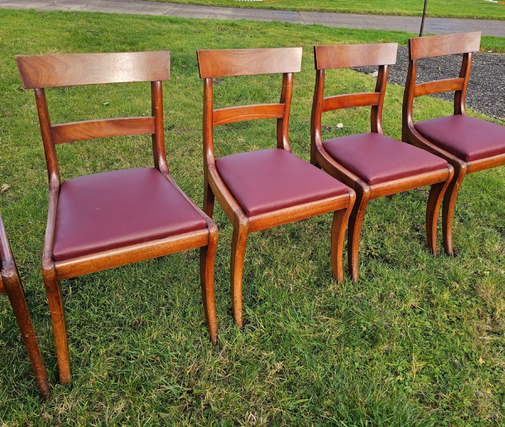 A matching set of six Regency mahogany dining chairs featuring curved sabre legs, horizontal bar backs, and burgundy leather seats. View V