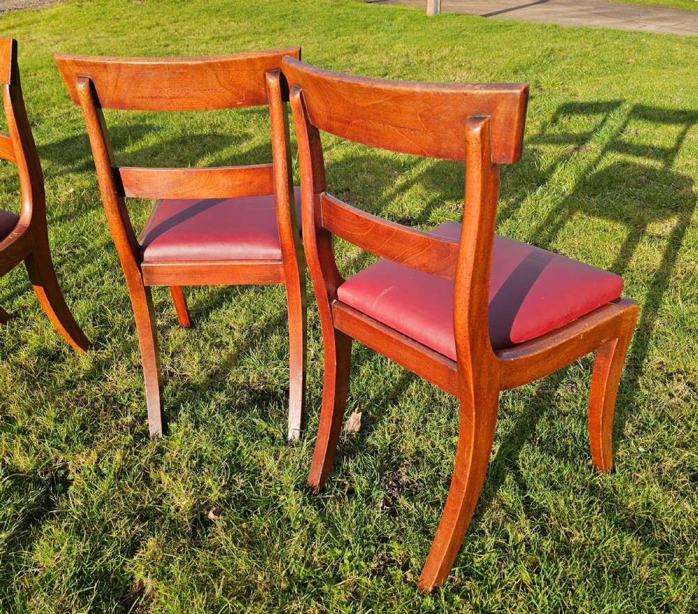 A matching set of six Regency mahogany dining chairs featuring curved sabre legs, horizontal bar backs, and burgundy leather seats. View VII