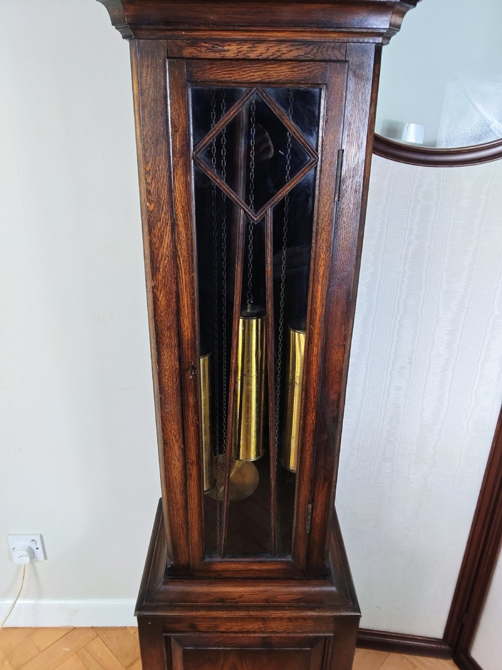 A dark oak longcase clock featuring an arched hood, a brass dial with silvered chapter ring, and an astragal glazed trunk door. View III