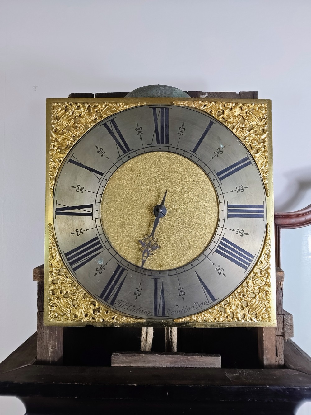 An antique Queen Anne ebonised longcase clock featuring a square brass dial with Roman numerals and ornate corner spandrels. View IV