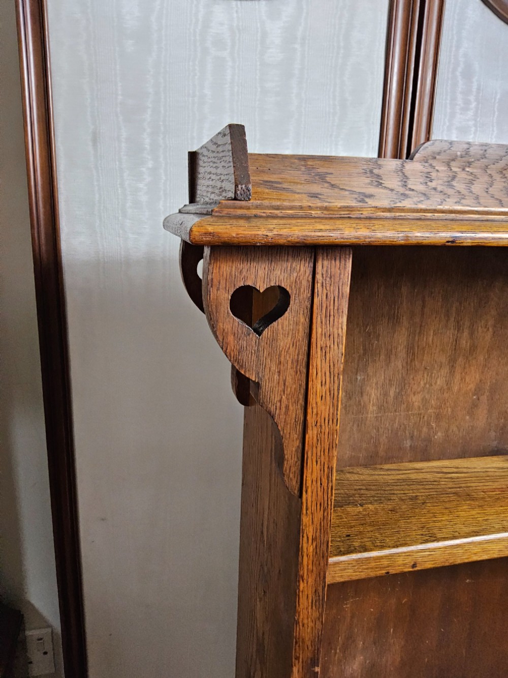 An Arts and Crafts solid oak open bookcase featuring three shelves and heart-shaped cutouts on the top gallery and side brackets. View II