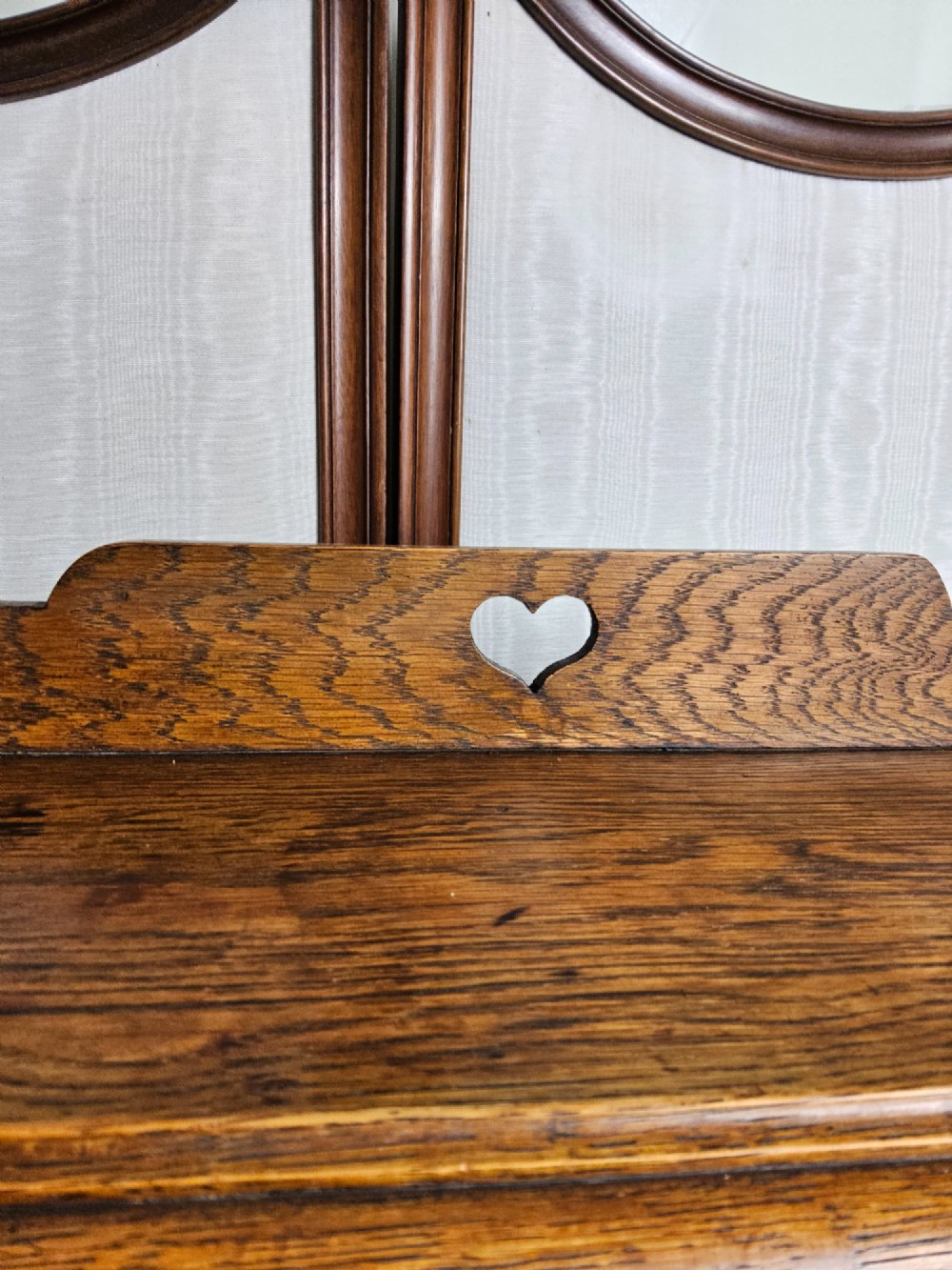 An Arts and Crafts solid oak open bookcase featuring three shelves and heart-shaped cutouts on the top gallery and side brackets. View III