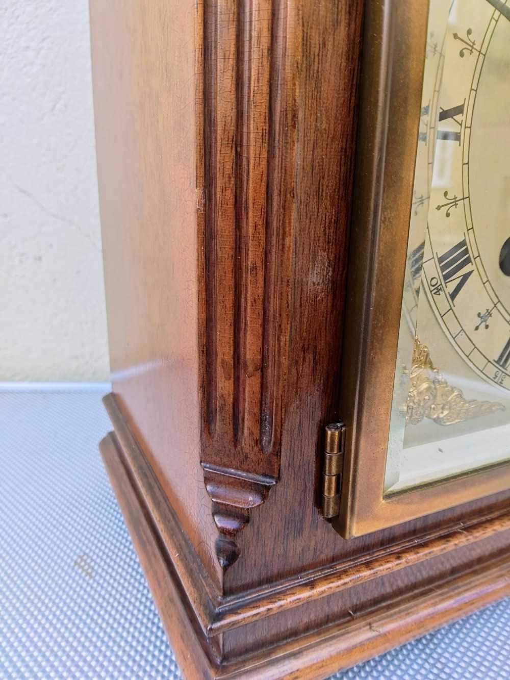 A square mahogany mantel clock featuring fluted side pilasters, brass bun feet, and a silvered dial with Roman numerals and corner brass spandrels. View V
