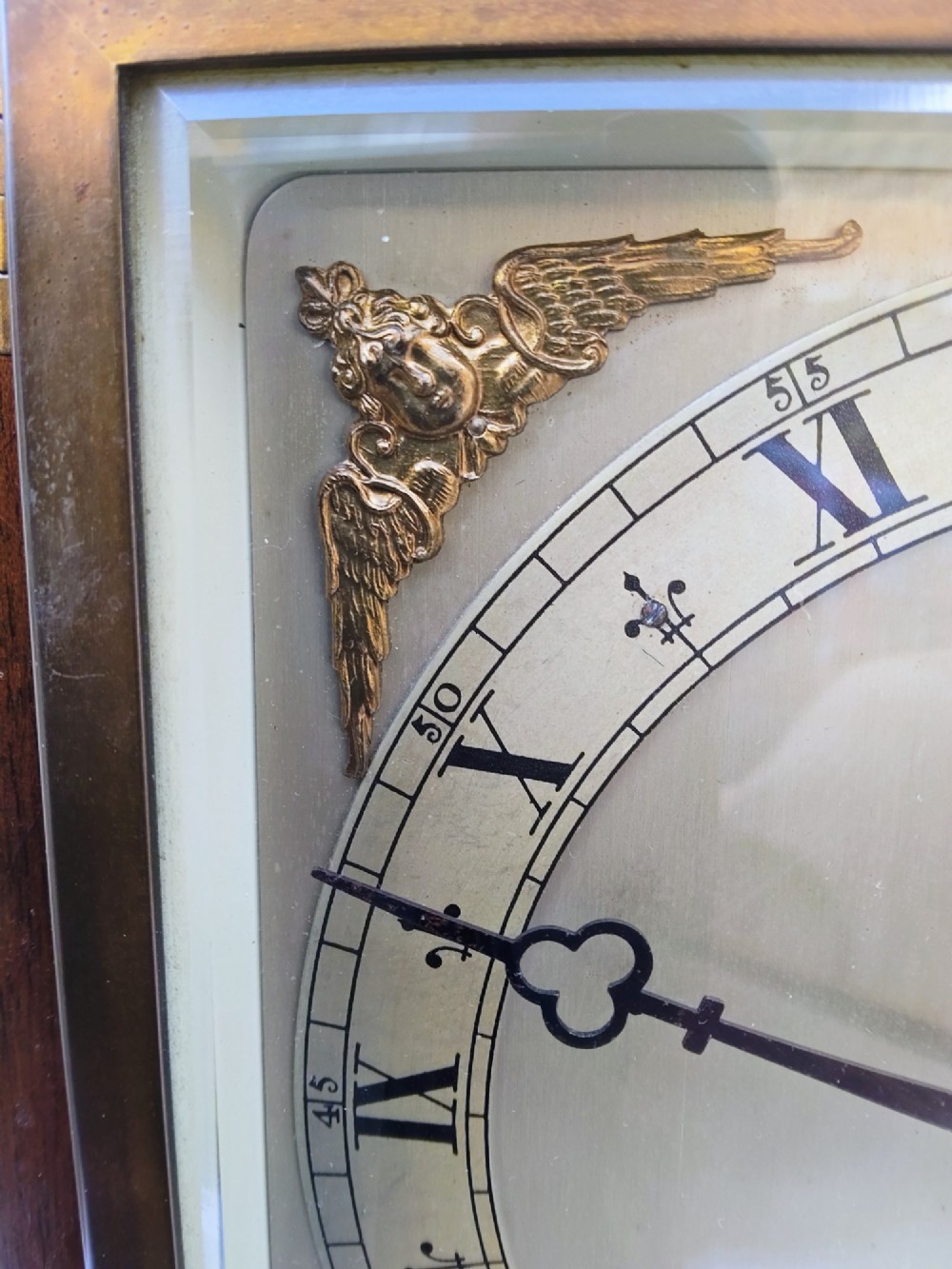 A square mahogany mantel clock featuring fluted side pilasters, brass bun feet, and a silvered dial with Roman numerals and corner brass spandrels. View VII