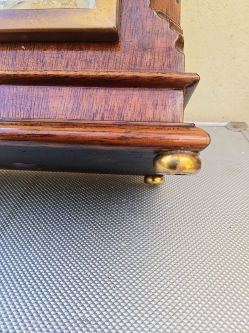 A square mahogany mantel clock featuring fluted side pilasters, brass bun feet, and a silvered dial with Roman numerals and corner brass spandrels. View IX