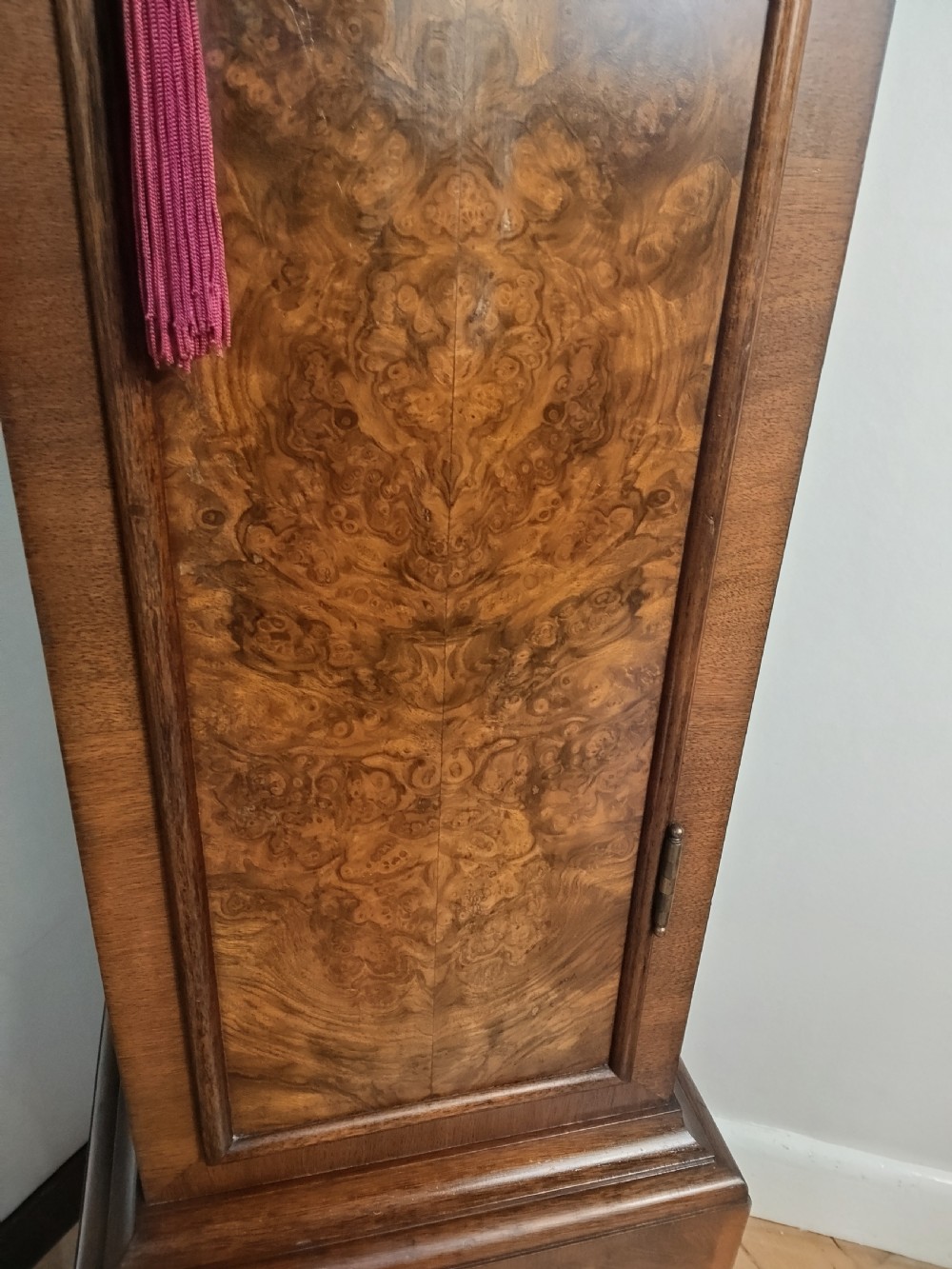 A floor-standing burr walnut grandmother longcase clock featuring a square brass dial, decorative corner spandrels, a coved top with metal finials, and a slender veneered trunk door. View II