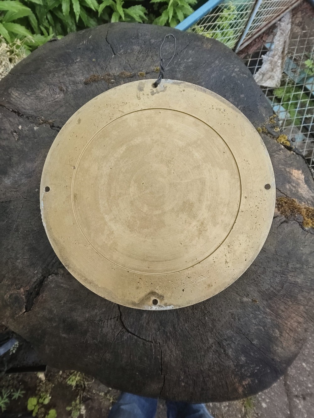 A circular antique brass marine bulkhead wall clock featuring a white dial with black Roman numerals and side latch fixtures. View VII