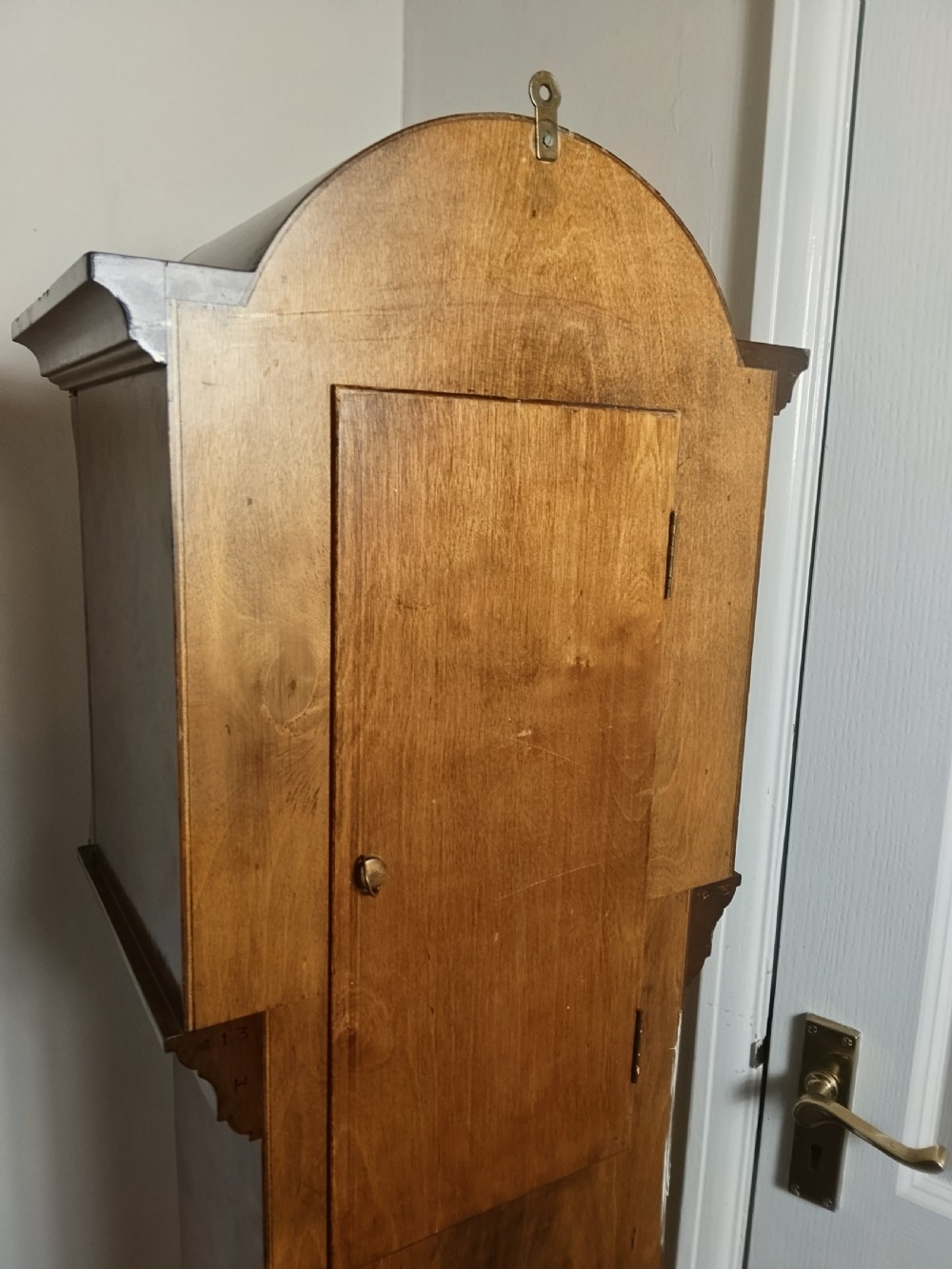A freestanding burr walnut grandmother clock featuring an arched hood, brass dial with Roman numerals, and a figure-matched veneered trunk. View VIII