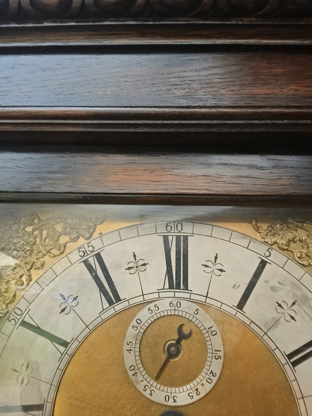 A tall dark oak longcase clock featuring rope twist columns, a square brass dial with silvered chapter ring, and a carved wooden casing. View VII