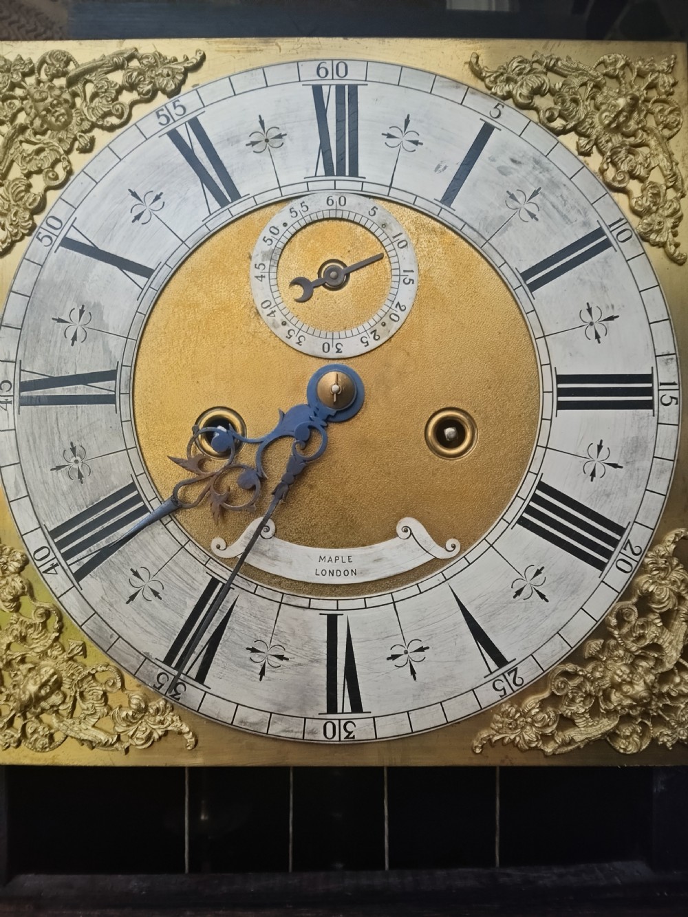 A tall dark oak longcase clock featuring rope twist columns, a square brass dial with silvered chapter ring, and a carved wooden casing. View IX