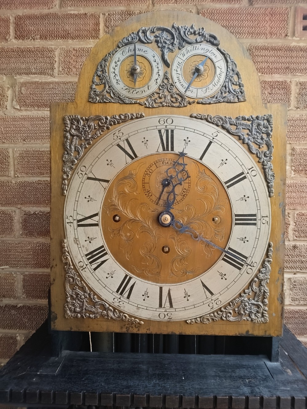 A tall dark oak longcase clock featuring an arched hood, barley twist columns, carved wood panels, and an ornate brass dial. View IV