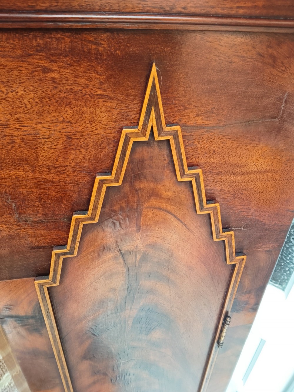 An antique flame mahogany longcase clock featuring a swan-neck pediment, brass finials, reeded columns, and a painted clock face with Roman numerals. View VI