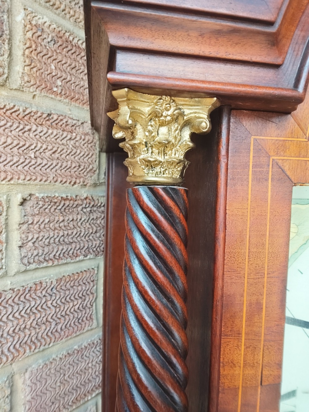 An antique flame mahogany longcase clock featuring a swan-neck pediment, brass finials, reeded columns, and a painted clock face with Roman numerals. View VII