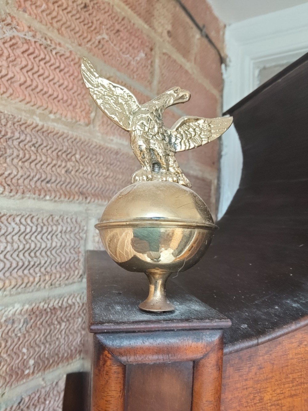 An antique flame mahogany longcase clock featuring a swan-neck pediment, brass finials, reeded columns, and a painted clock face with Roman numerals. View IX