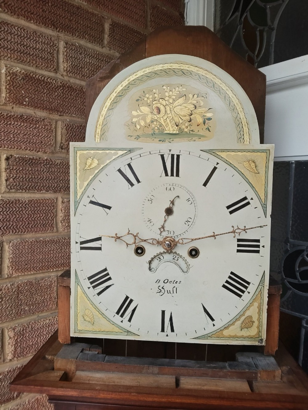An antique flame mahogany longcase clock featuring a swan-neck pediment, brass finials, reeded columns, and a painted clock face with Roman numerals. View XIII