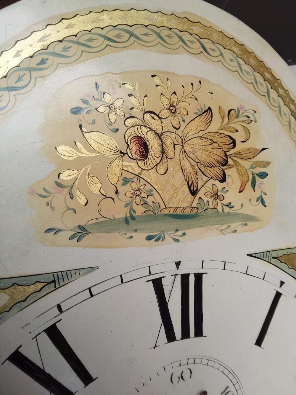 An antique flame mahogany longcase clock featuring a swan-neck pediment, brass finials, reeded columns, and a painted clock face with Roman numerals. View XV