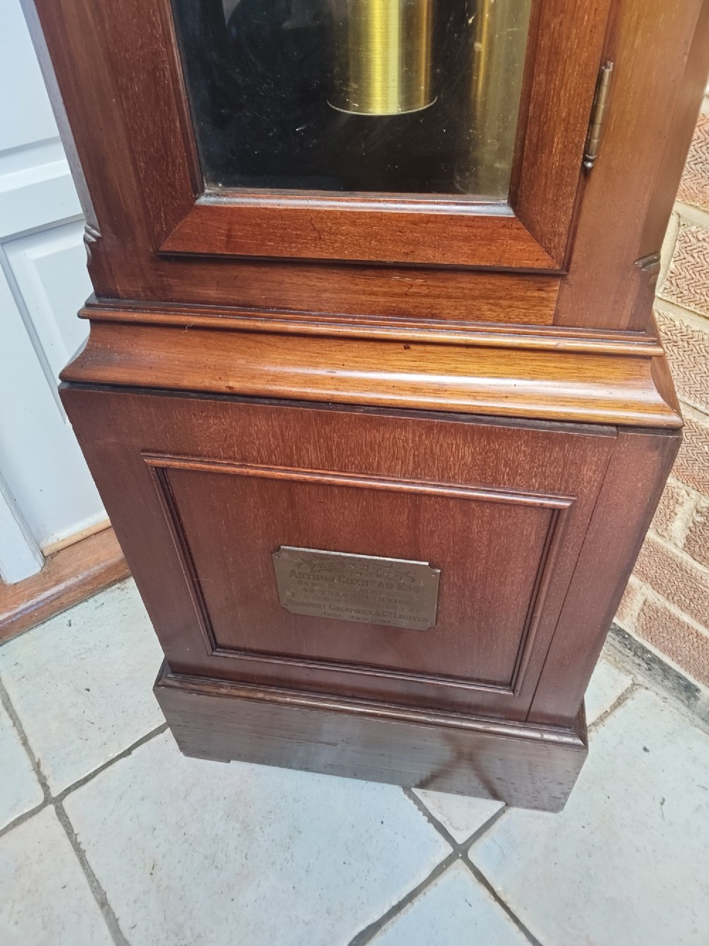 A tall wooden longcase clock featuring an arched hood, silvered brass dial, and a glazed door showcasing internal brass weights and pendulum. View XIII