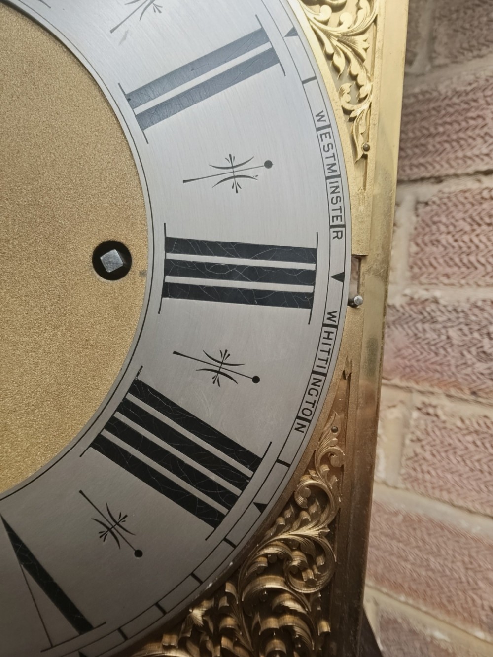 A tall wooden longcase clock featuring an arched hood, silvered brass dial, and a glazed door showcasing internal brass weights and pendulum. View XIV