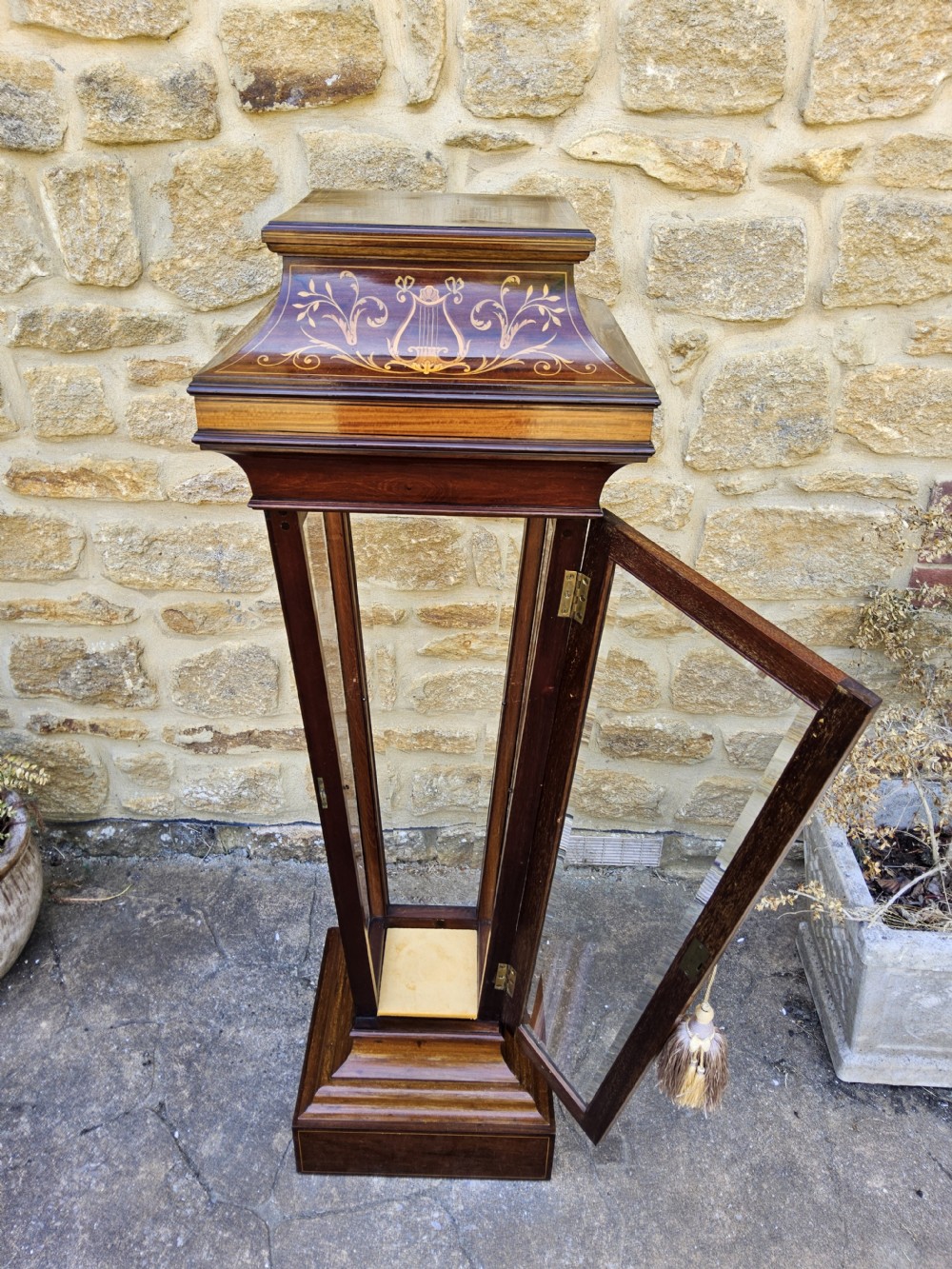 A tall Edwardian mahogany pedestal display cabinet featuring inlaid floral motifs, glazed side panels, and a tapered rectangular form. View IV