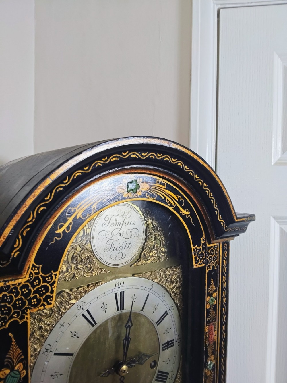 A slender black lacquer grandmother clock decorated with gilded chinoiserie landscape motifs and fitted with an arched brass dial. View VI