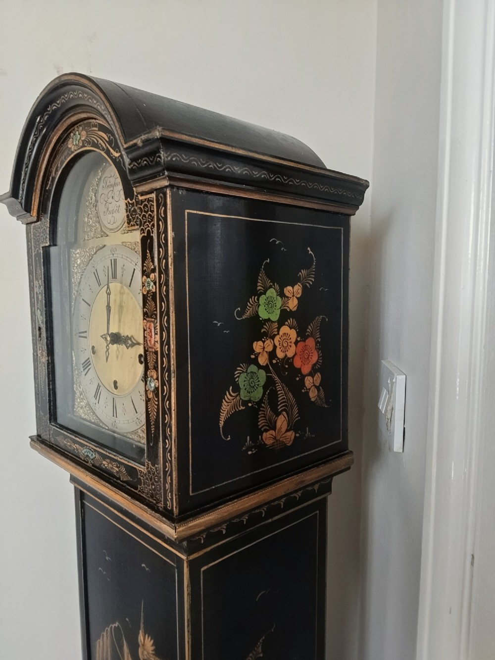 A slender black lacquer grandmother clock decorated with gilded chinoiserie landscape motifs and fitted with an arched brass dial. View VII