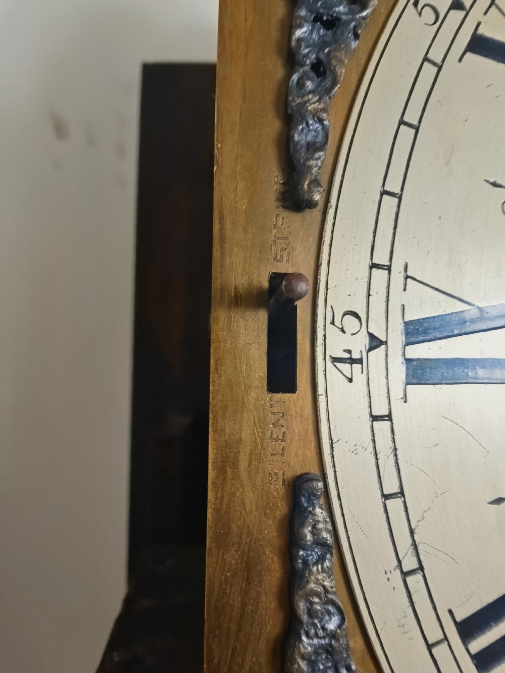 A tall dark oak longcase clock featuring an arched bonnet, barley twist side columns, a brass dial with Roman numerals, and a glazed trunk door displaying three brass weights and pendulum. View IX