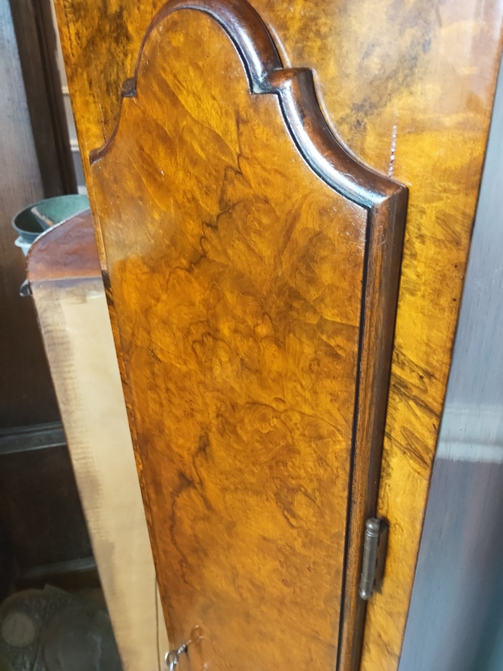 A tall slim figured walnut grandmother longcase clock featuring an arched hood, brass and silvered dial, and a polished wood trunk. View II