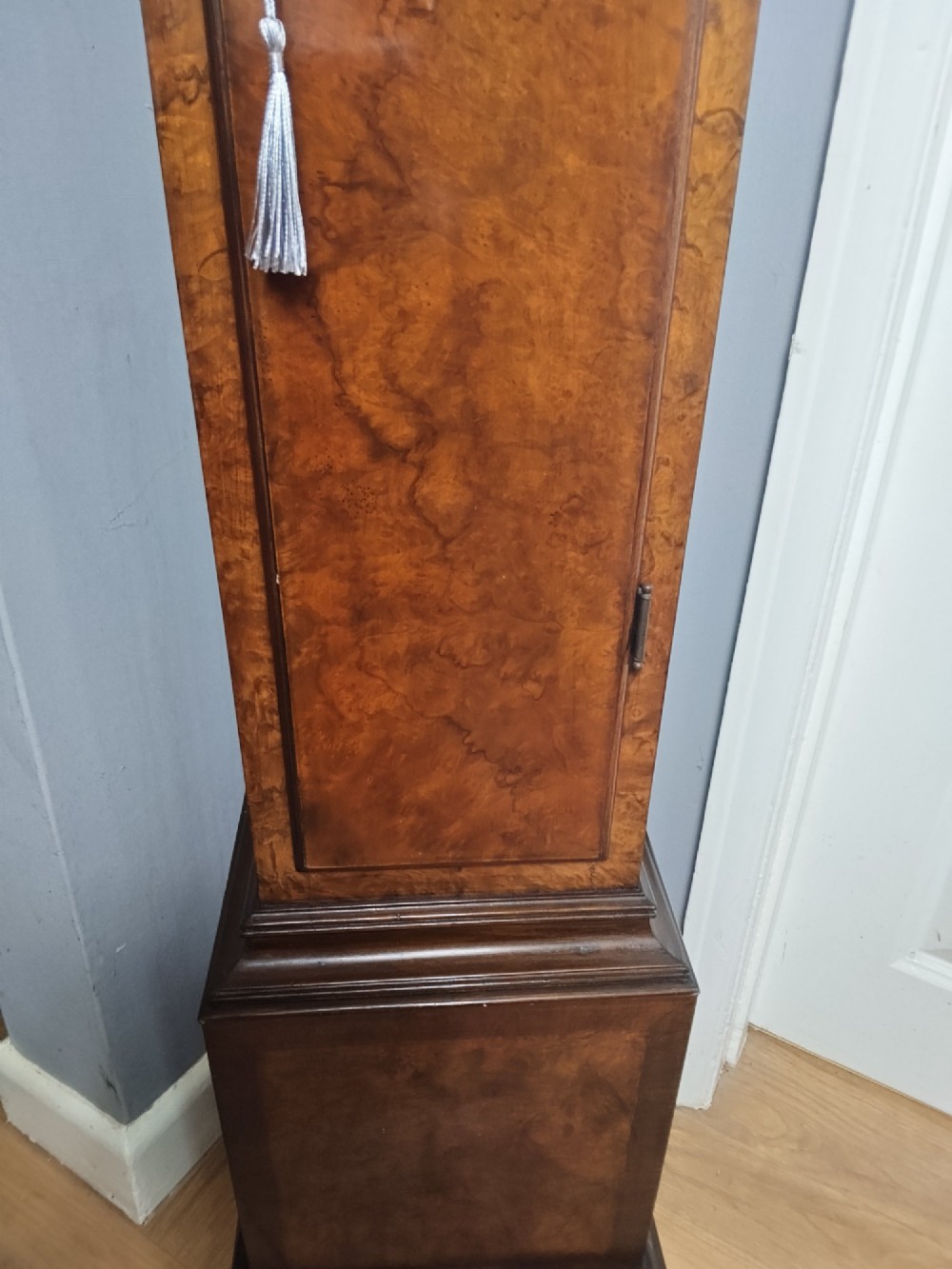 A tall slim figured walnut grandmother longcase clock featuring an arched hood, brass and silvered dial, and a polished wood trunk. View IV