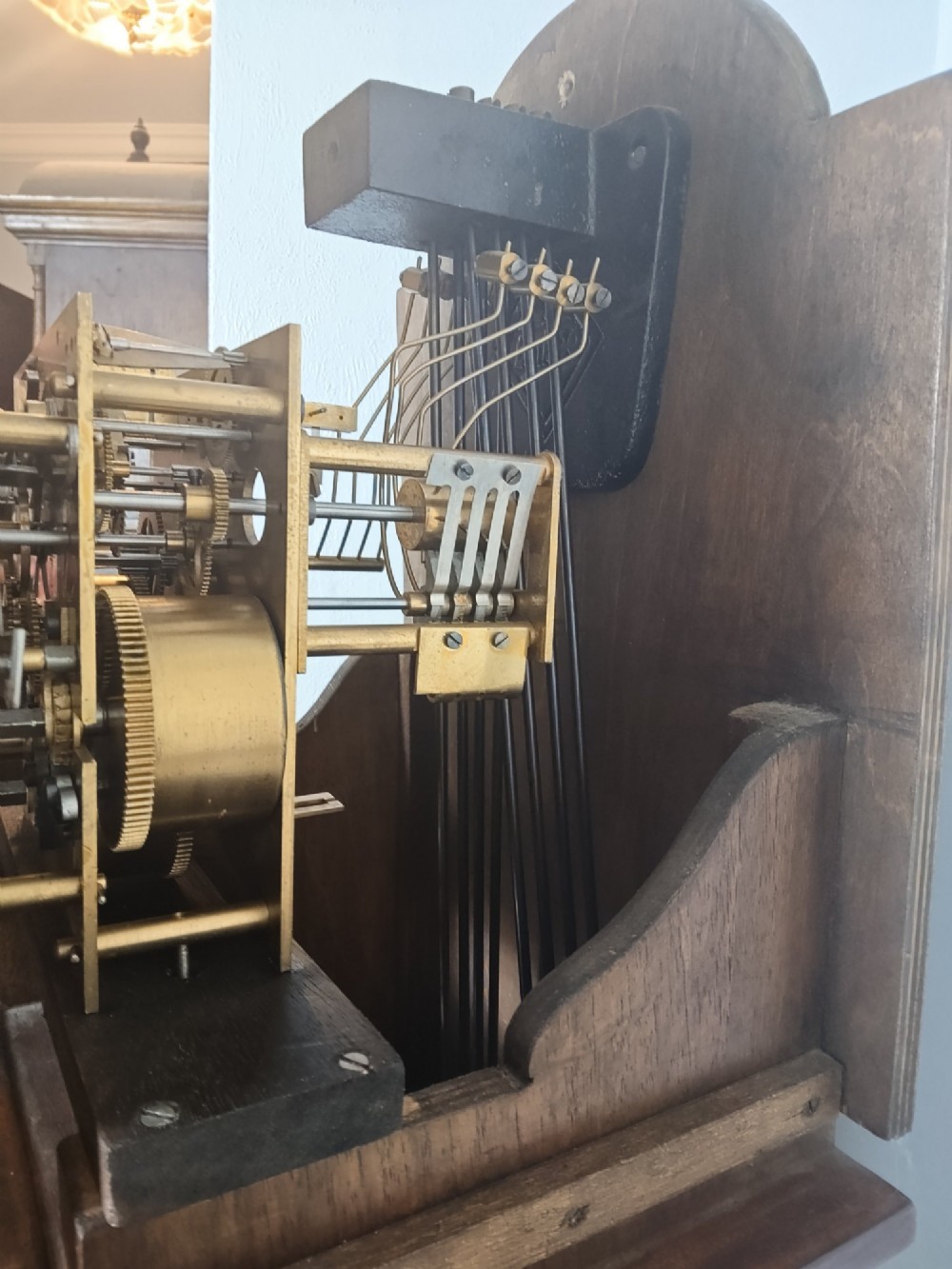 A tall slim figured walnut grandmother longcase clock featuring an arched hood, brass and silvered dial, and a polished wood trunk. View X