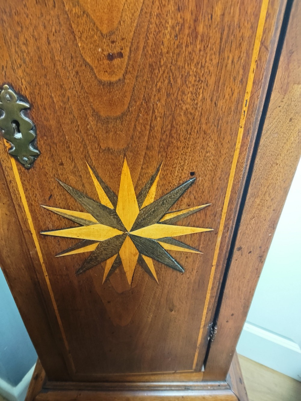 A tall Georgian mahogany longcase clock featuring a square brass dial, starburst marquetry inlay on the trunk door, and a stepped top pediment. View II