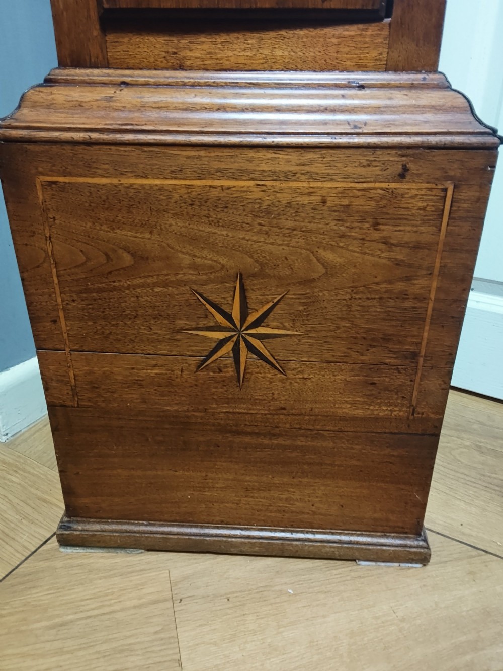 A tall Georgian mahogany longcase clock featuring a square brass dial, starburst marquetry inlay on the trunk door, and a stepped top pediment. View III