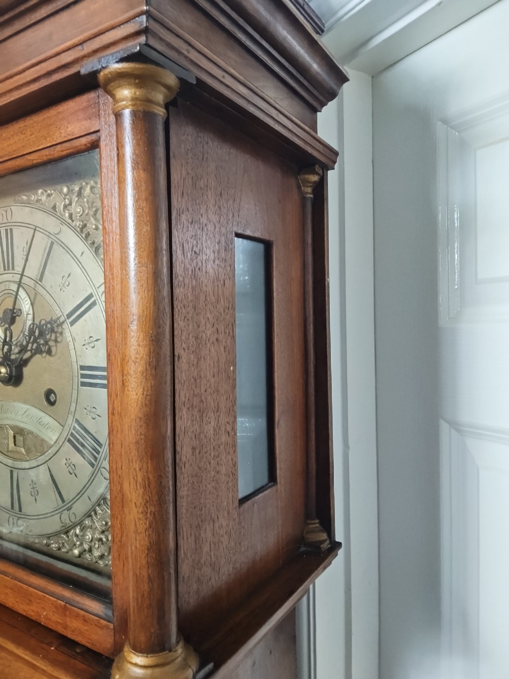 A tall Georgian mahogany longcase clock featuring a square brass dial, starburst marquetry inlay on the trunk door, and a stepped top pediment. View VI