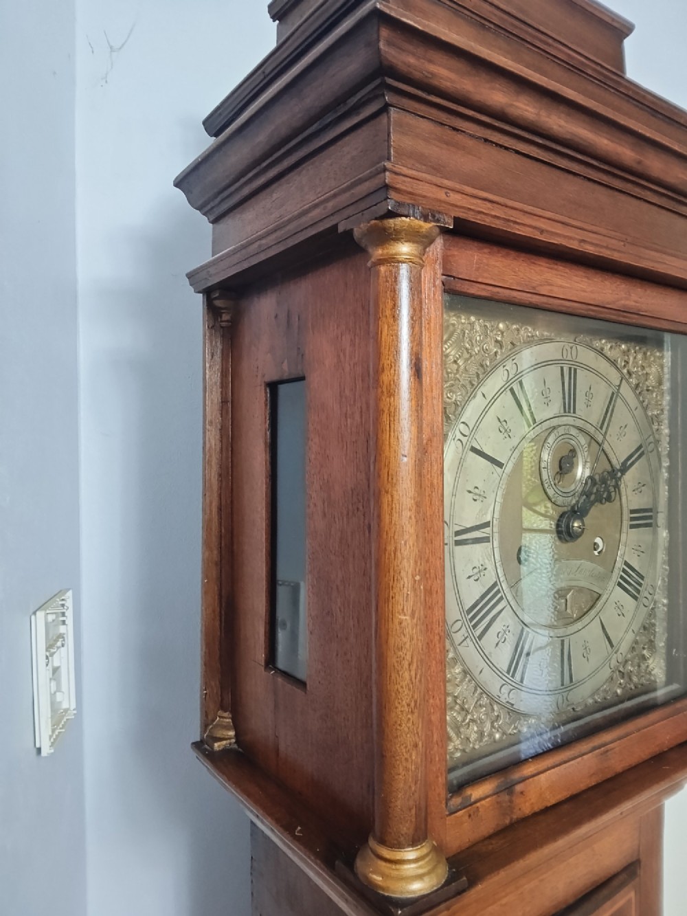 A tall Georgian mahogany longcase clock featuring a square brass dial, starburst marquetry inlay on the trunk door, and a stepped top pediment. View VII