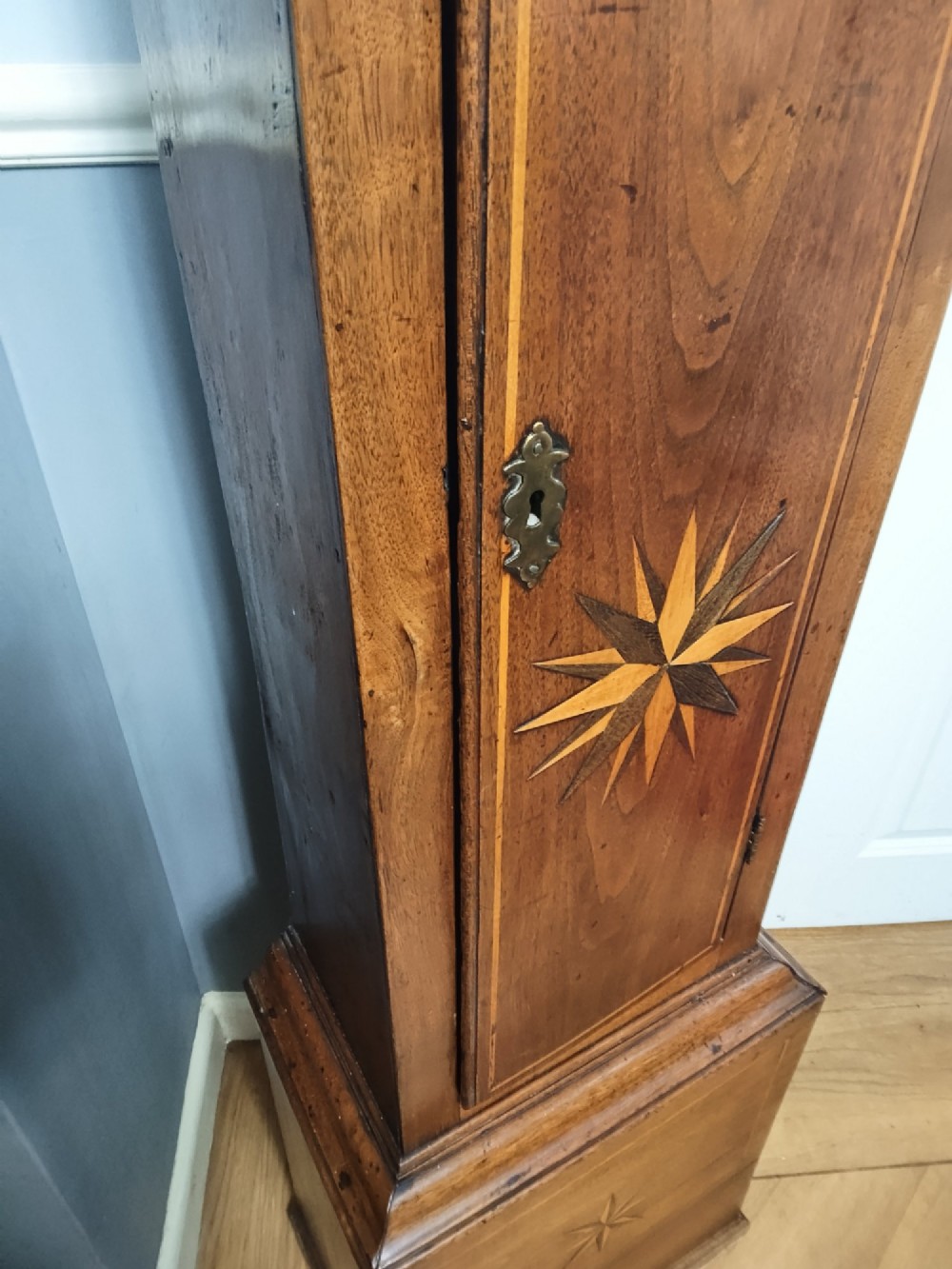 A tall Georgian mahogany longcase clock featuring a square brass dial, starburst marquetry inlay on the trunk door, and a stepped top pediment. View XIII