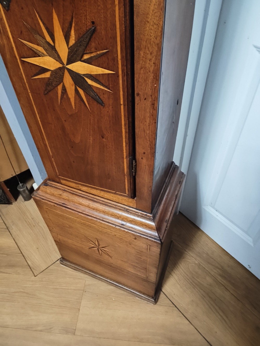 A tall Georgian mahogany longcase clock featuring a square brass dial, starburst marquetry inlay on the trunk door, and a stepped top pediment. View XIV