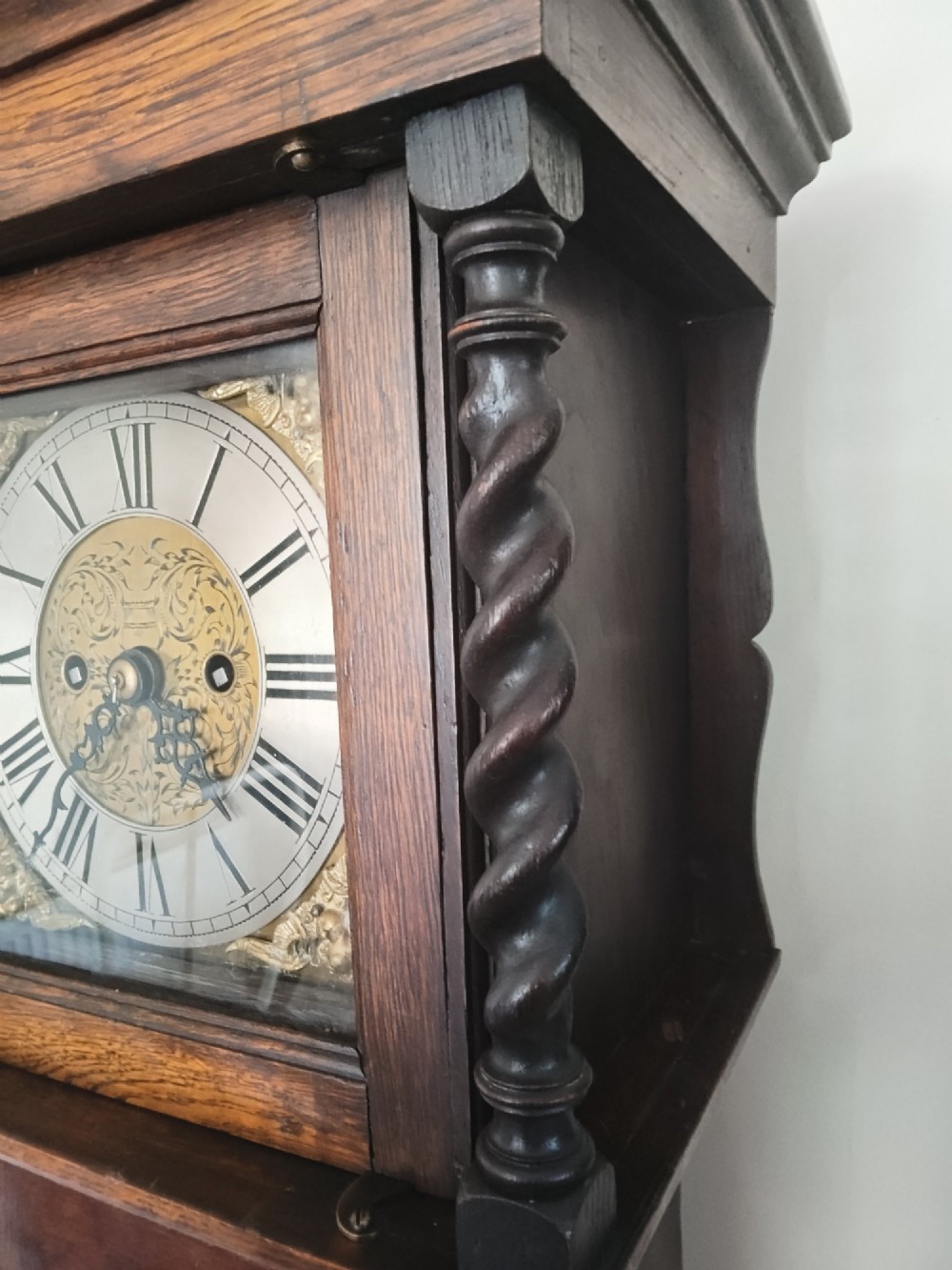 A 19th-century dark oak grandmother clock featuring barley twist side pillars, a square glass hood, and a brass dial with Roman numerals. View II