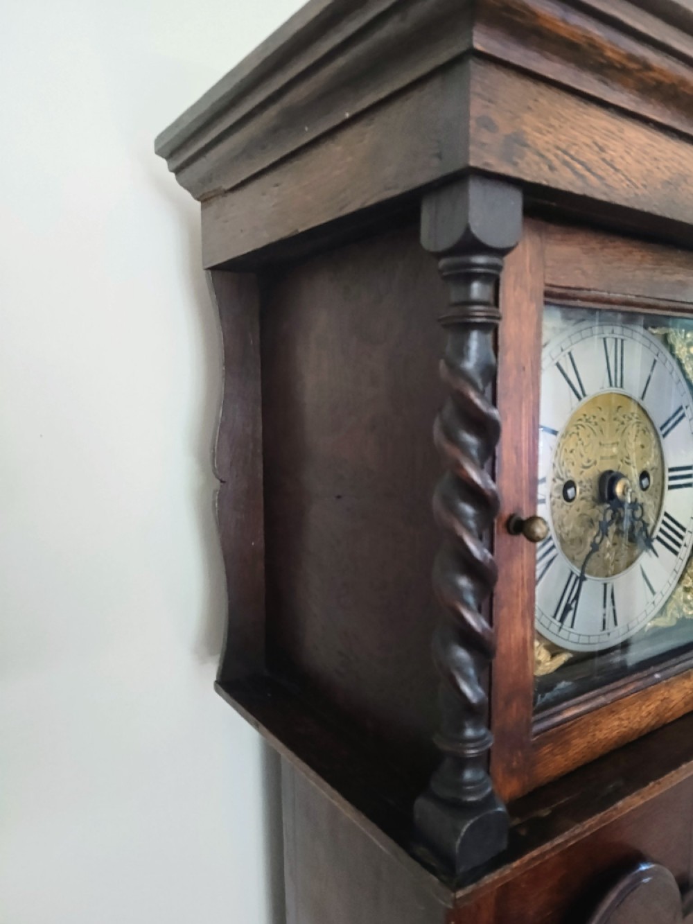 A 19th-century dark oak grandmother clock featuring barley twist side pillars, a square glass hood, and a brass dial with Roman numerals. View III
