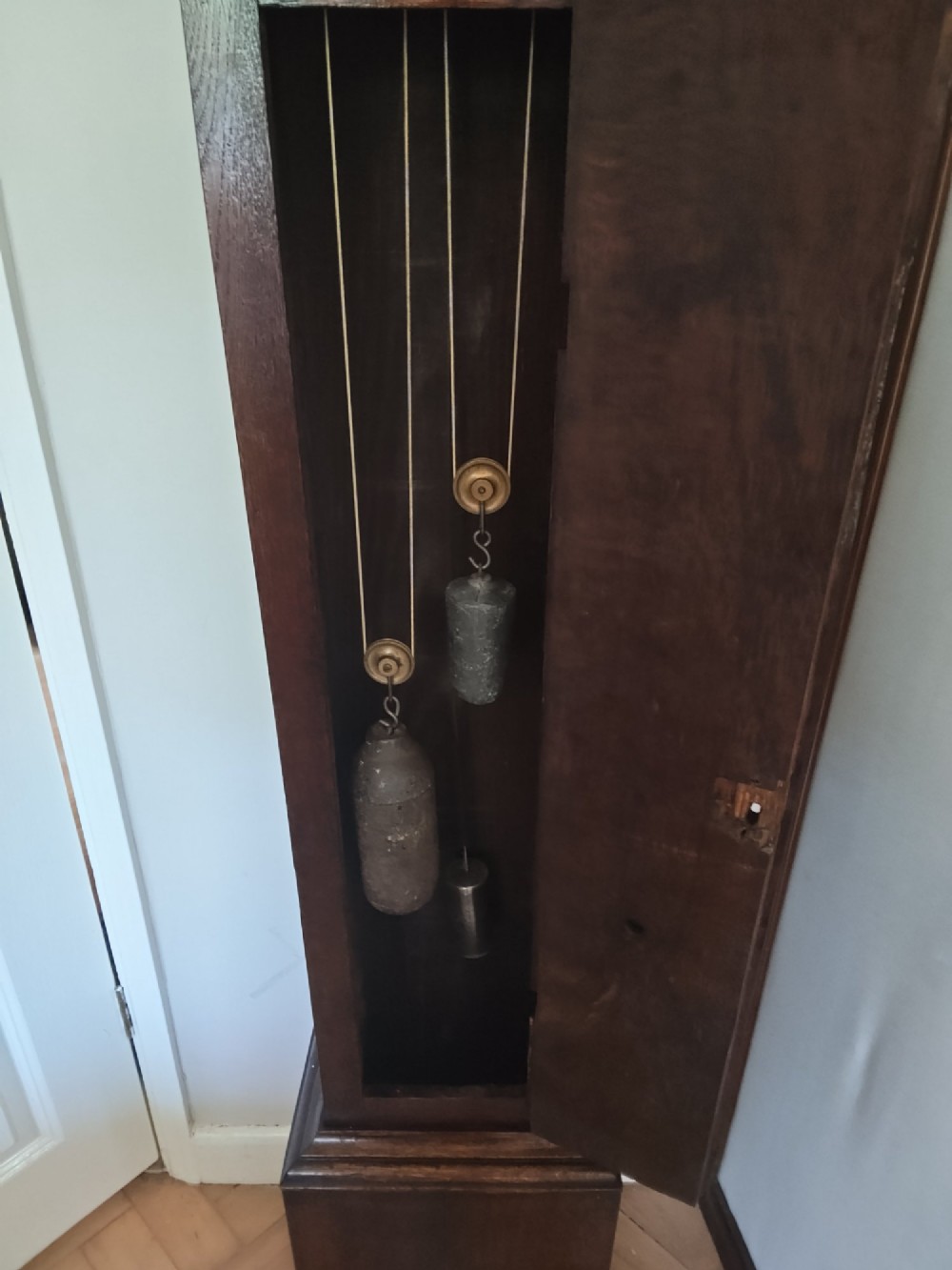 A 19th-century dark oak grandmother clock featuring barley twist side pillars, a square glass hood, and a brass dial with Roman numerals. View VIII