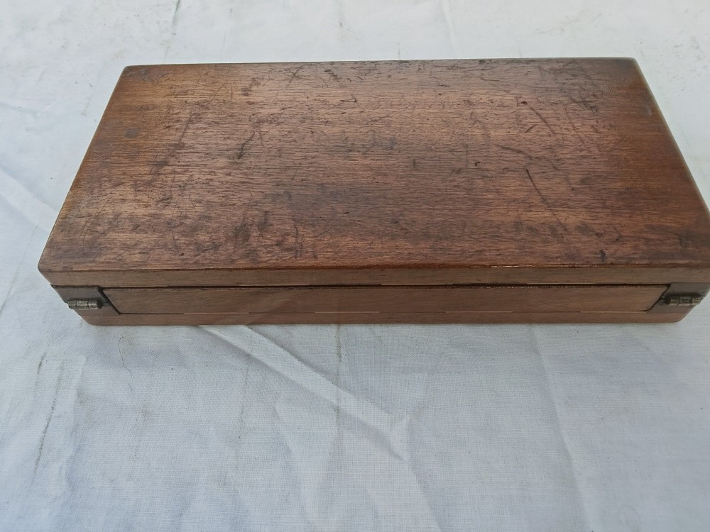 An open antique mahogany folding travelling chess board containing miniature carved red and natural white bone chess pieces fitted into individual pegged holes. View V