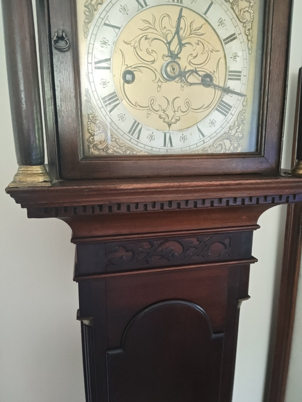 A slim dark mahogany longcase clock featuring a swan-neck pediment, brass dial with Roman numerals, and an arched trunk door. View X