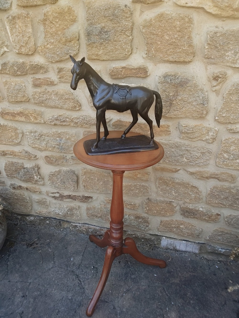 A dark brown cast bronze sculpture depicting a saddled standing horse positioned on an integral rectangular base. View II