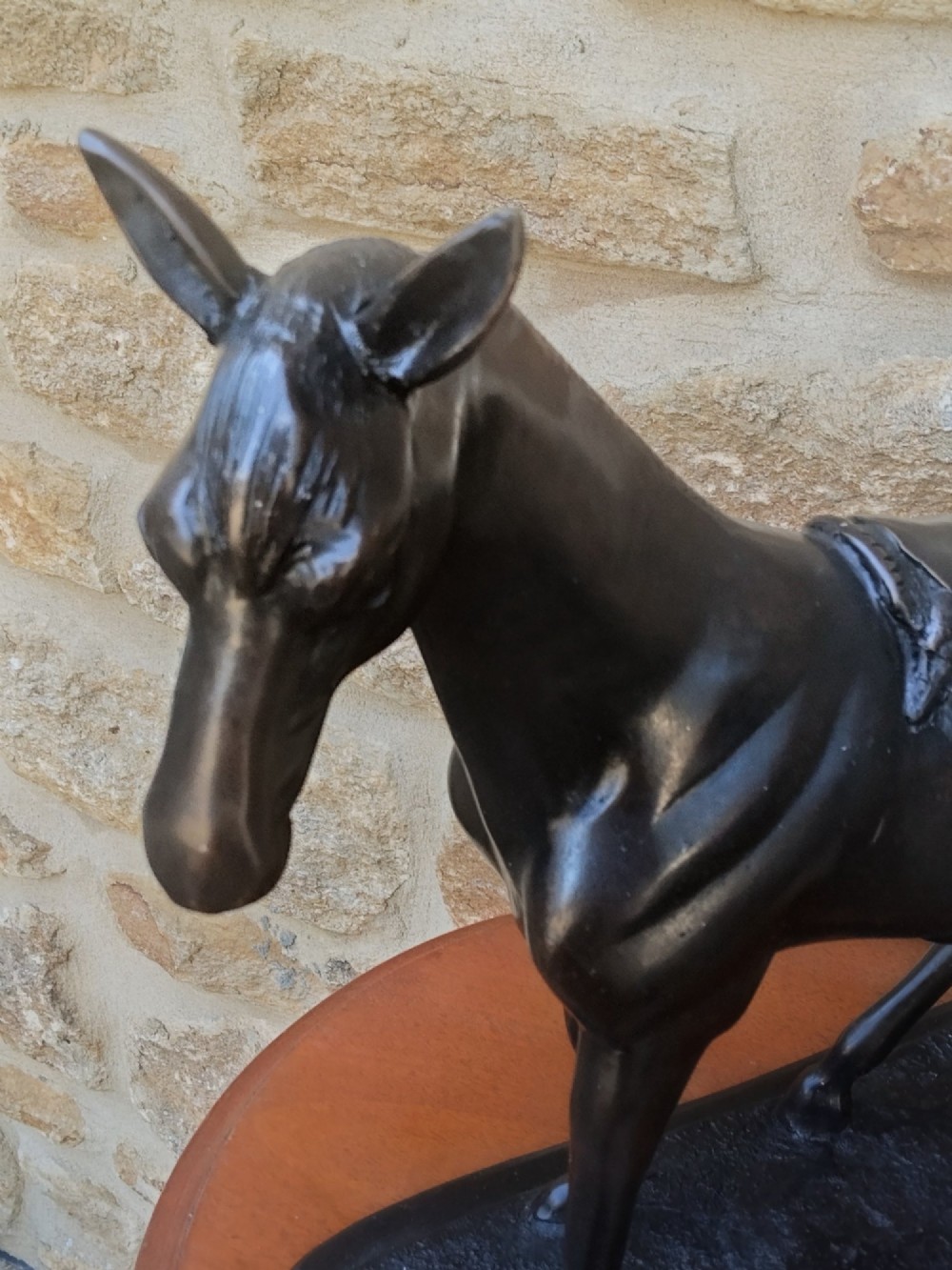 A dark brown cast bronze sculpture depicting a saddled standing horse positioned on an integral rectangular base. View IV